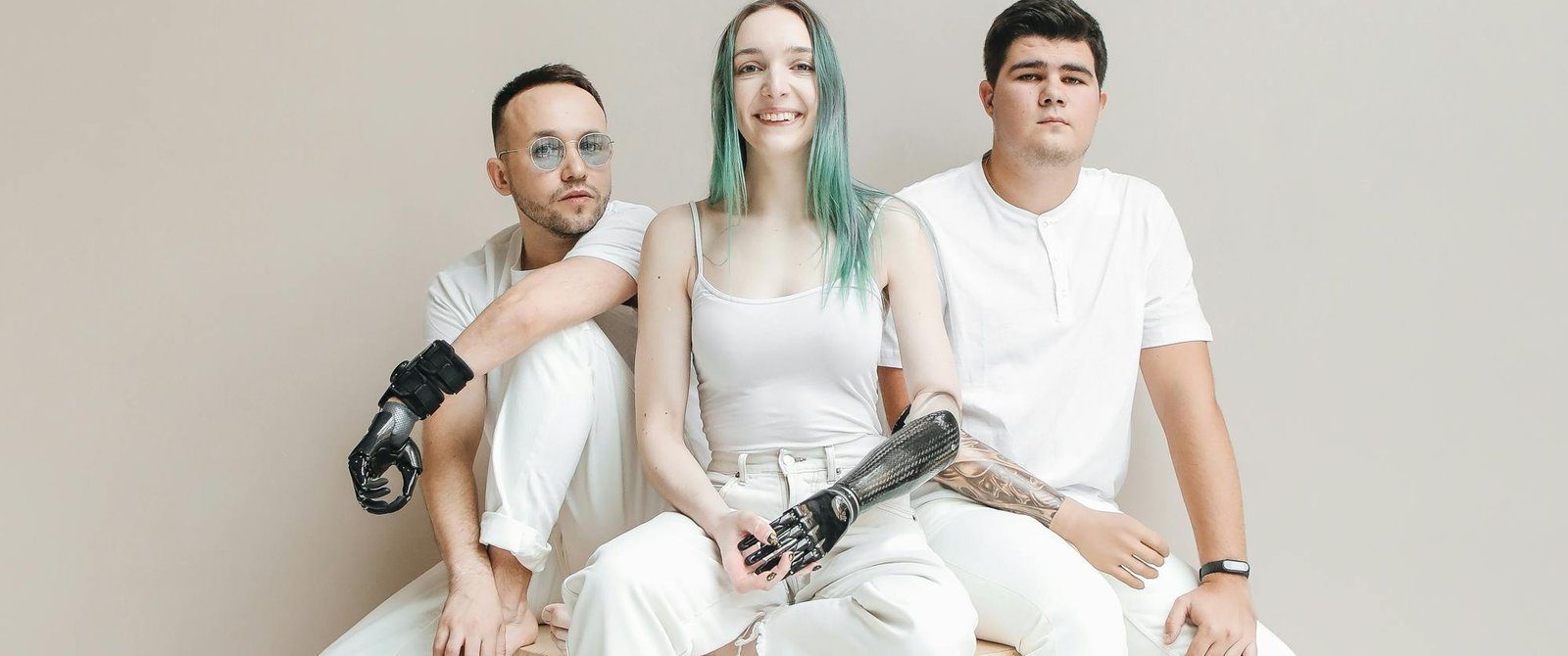 Three people, two with prosthetic arms, sitting together